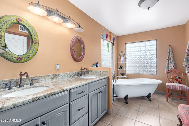 full bathroom with tile patterned floors, a freestanding tub, double vanity, and a sink