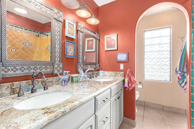 bathroom featuring tile patterned flooring, double vanity, toilet, and a sink