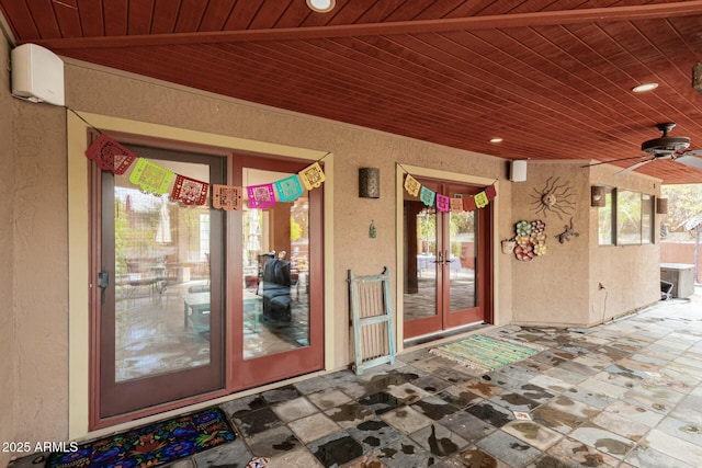 view of exterior entry featuring stucco siding, french doors, and a ceiling fan