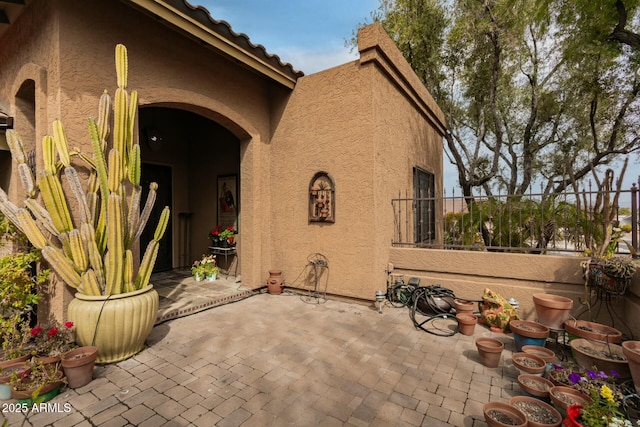 entrance to property featuring stucco siding, fence, and a patio area