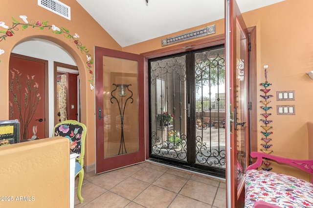 tiled entrance foyer with vaulted ceiling, arched walkways, and visible vents