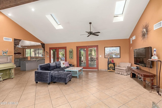 living room with light tile patterned floors, visible vents, french doors, and a skylight