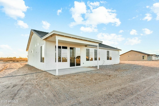 back of property with stucco siding and a patio