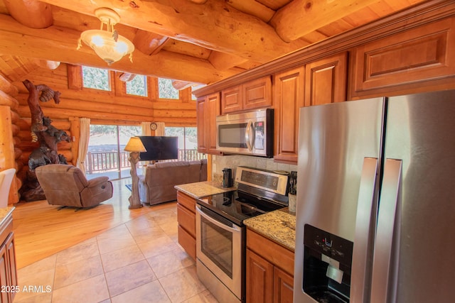 6168 W Hidden Pines Loop, Pine, AZ 85544 - kitchen with stainless steel appliances, log walls, open floor plan, brown cabinets, and tasteful backsplash