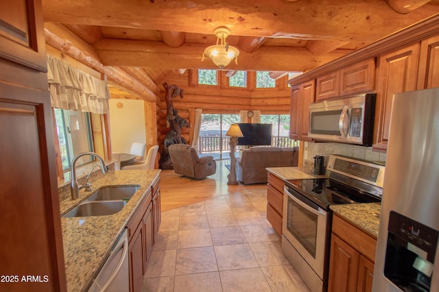 6168 W Hidden Pines Loop, Pine, AZ 85544 - kitchen with appliances with stainless steel finishes, rustic walls, a sink, open floor plan, and brown cabinets