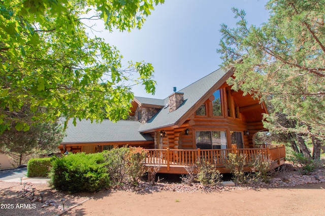 6168 W Hidden Pines Loop, Pine, AZ 85544 - view of front of house featuring log siding, a wooden deck, a chimney, and roof with shingles