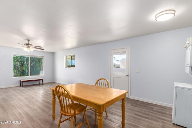 dining area featuring hardwood / wood-style flooring, stacked washer / drying machine, and a wealth of natural light