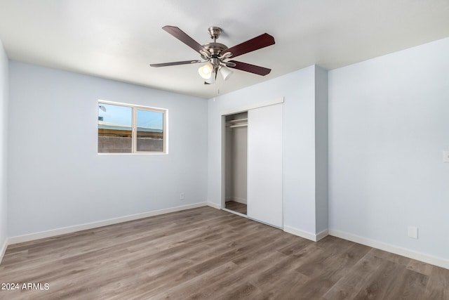 unfurnished bedroom featuring ceiling fan, a closet, and hardwood / wood-style floors