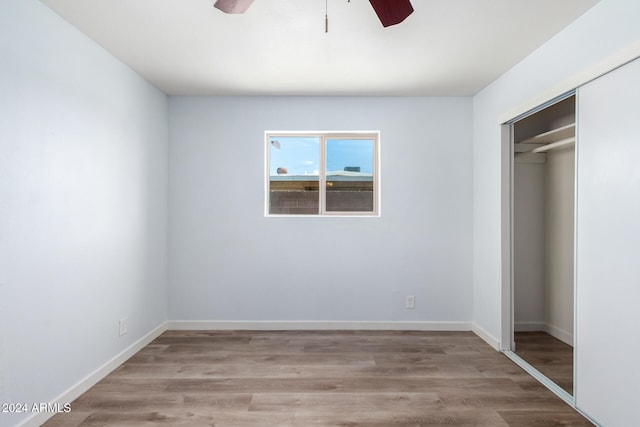 unfurnished bedroom featuring ceiling fan, a closet, and hardwood / wood-style floors