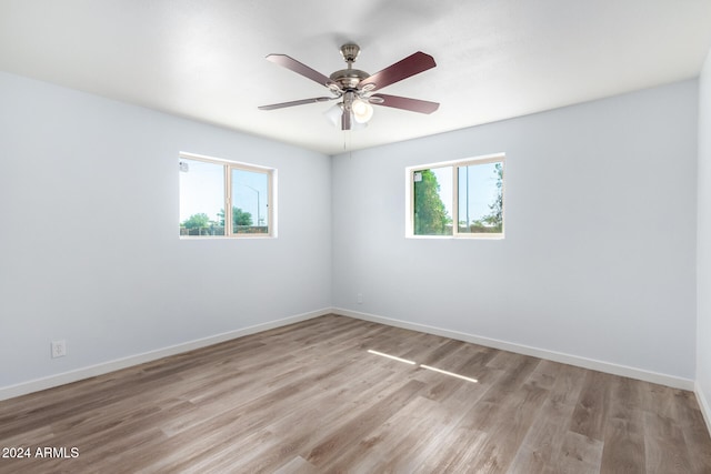 empty room featuring ceiling fan, light hardwood / wood-style flooring, and a wealth of natural light