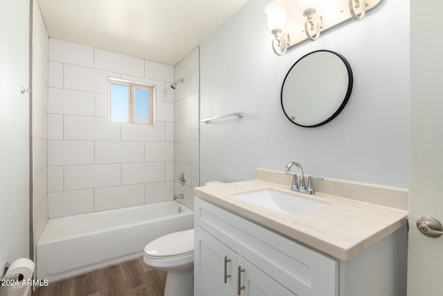 full bathroom with tiled shower / bath, vanity, hardwood / wood-style floors, and toilet