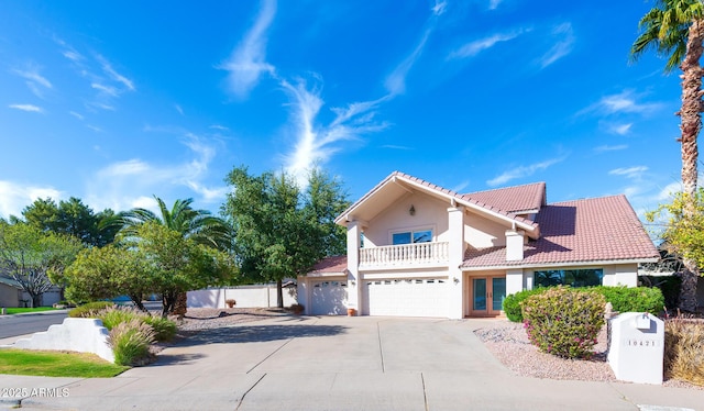 view of front of property with concrete driveway, a balcony, a tile roof, an attached garage, and french doors