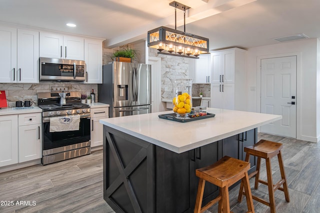 kitchen with stainless steel appliances, white cabinetry, tasteful backsplash, and decorative light fixtures