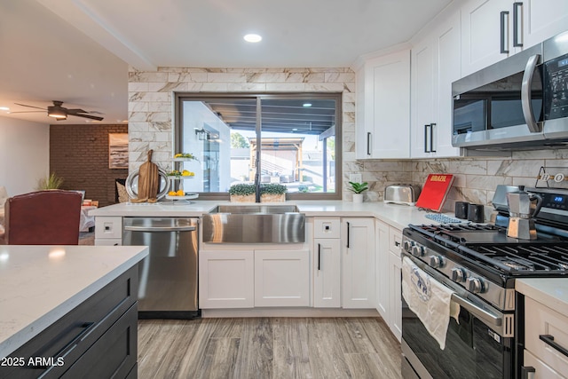 kitchen featuring light hardwood / wood-style flooring, sink, white cabinets, tasteful backsplash, and stainless steel appliances