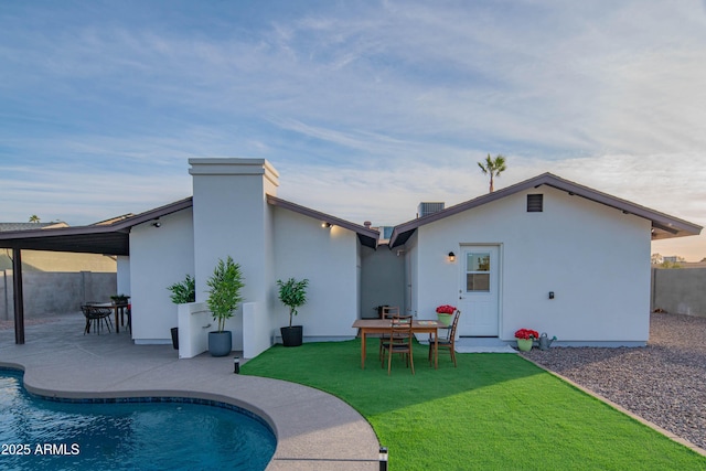 back of property featuring a fenced in pool, a patio area, and a lawn