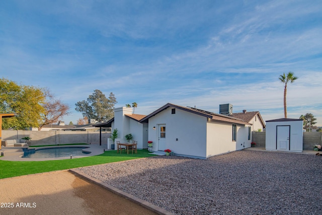 rear view of house with a fenced in pool, a patio, a shed, and central AC