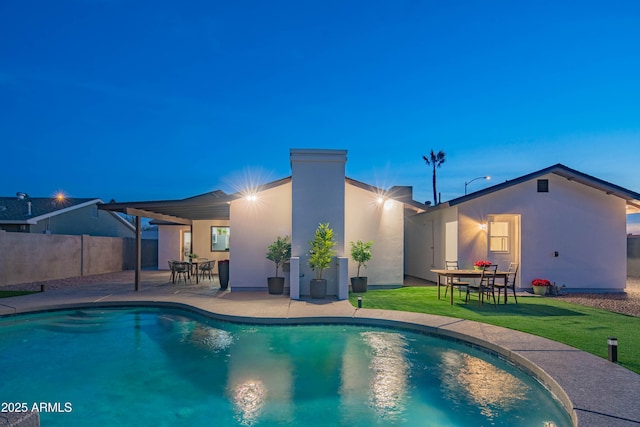 pool at dusk featuring a patio and a yard