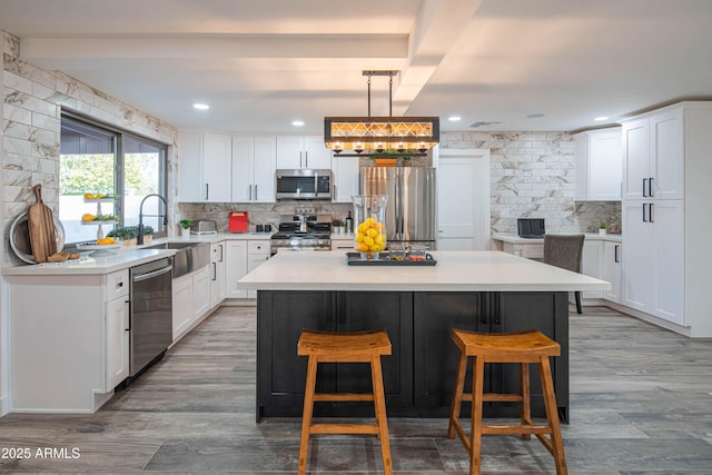 kitchen with sink, a kitchen island, white cabinetry, and appliances with stainless steel finishes