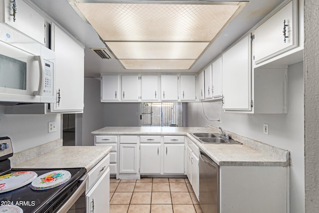 kitchen featuring sink, appliances with stainless steel finishes, light tile patterned floors, and white cabinetry