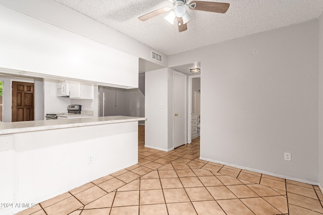 kitchen featuring kitchen peninsula, stainless steel range with electric stovetop, white cabinets, light tile patterned floors, and a textured ceiling