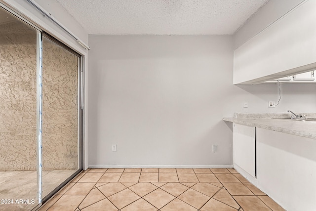 interior space featuring sink, light tile patterned floors, and a textured ceiling