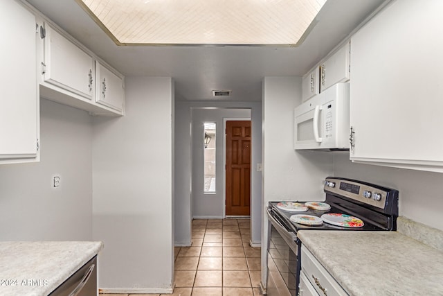 kitchen featuring stainless steel range with electric cooktop, light tile patterned floors, and white cabinetry