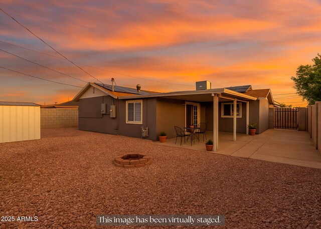 1113 E 5th St, Casa Grande, AZ 85122 - rear view of house featuring a fenced backyard, a fire pit, roof mounted solar panels, and a storage unit