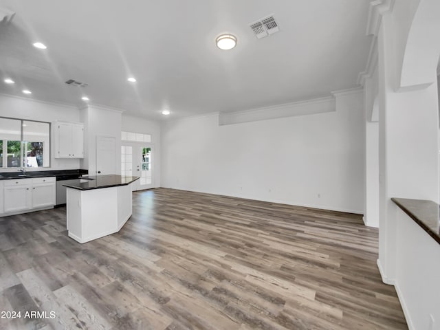 kitchen featuring wood-type flooring, a kitchen island, white cabinets, and ornamental molding