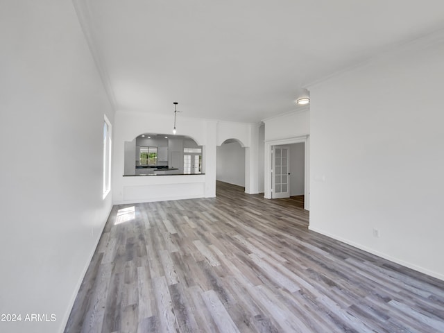 unfurnished living room with wood-type flooring and crown molding