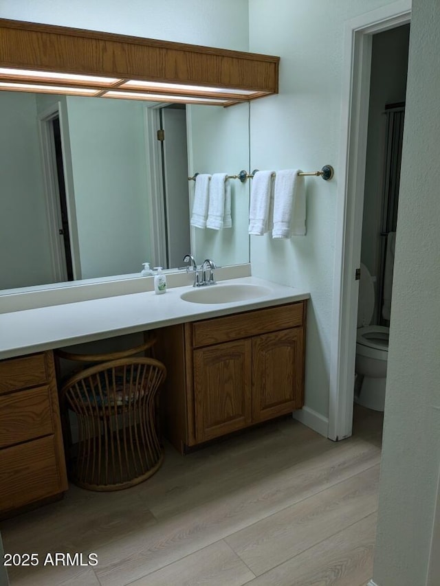 bathroom featuring vanity, toilet, and wood finished floors