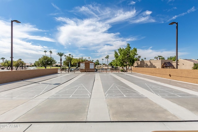 view of home's community with shuffleboard and fence