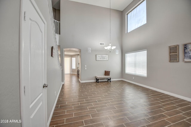 entryway with arched walkways, visible vents, baseboards, wood tiled floor, and an inviting chandelier