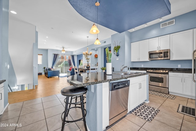 kitchen featuring hanging light fixtures, stainless steel appliances, sink, light wood-type flooring, and white cabinets