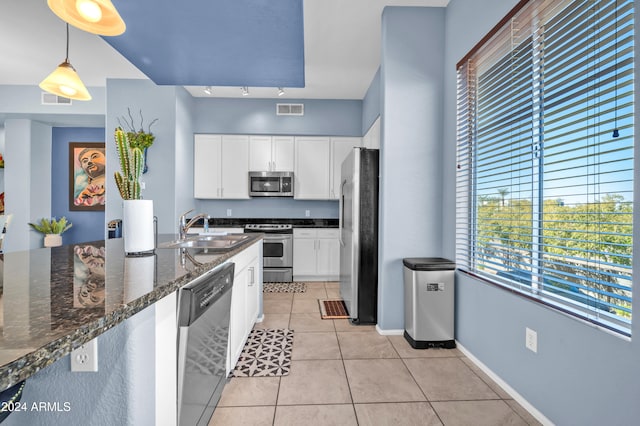 kitchen featuring sink, stainless steel appliances, dark stone counters, pendant lighting, and white cabinets