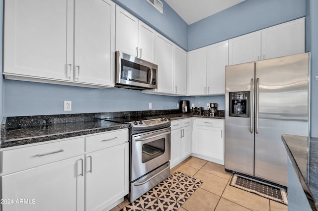 kitchen featuring white cabinets, dark stone counters, stainless steel appliances, and light tile patterned floors