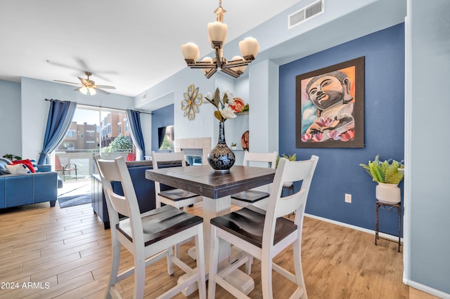 dining room with light hardwood / wood-style flooring and ceiling fan with notable chandelier