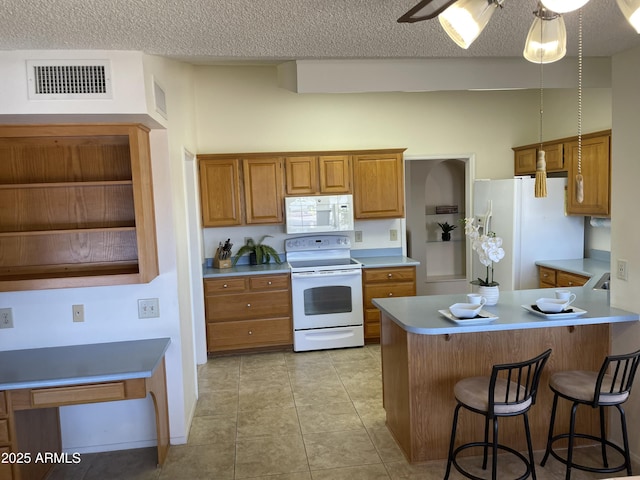 kitchen featuring ceiling fan, white appliances, a textured ceiling, and kitchen peninsula