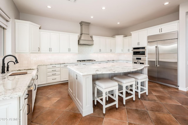 kitchen featuring white cabinetry, appliances with stainless steel finishes, a sink, and custom range hood
