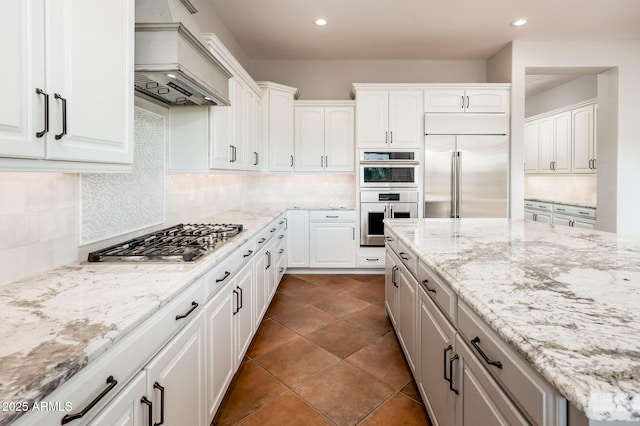 kitchen featuring white cabinetry, custom exhaust hood, tasteful backsplash, and stainless steel appliances