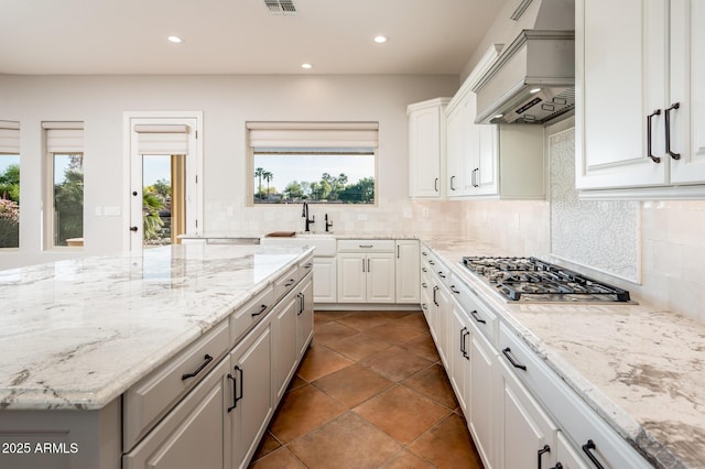 kitchen with a sink, stainless steel gas cooktop, recessed lighting, decorative backsplash, and custom exhaust hood