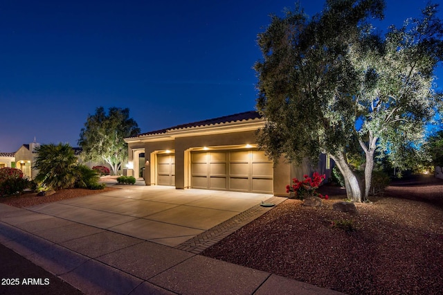 view of front of property featuring a tiled roof, a garage, stucco siding, and driveway