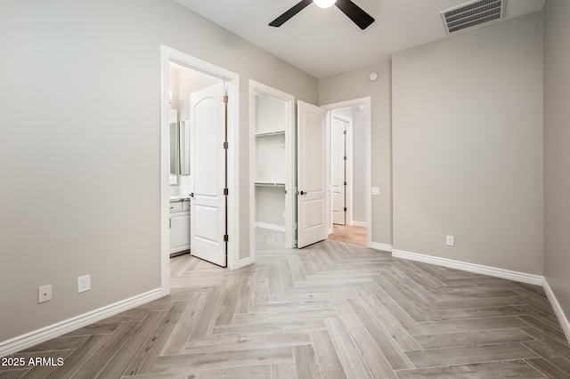 unfurnished bedroom with ceiling fan, visible vents, baseboards, connected bathroom, and a spacious closet