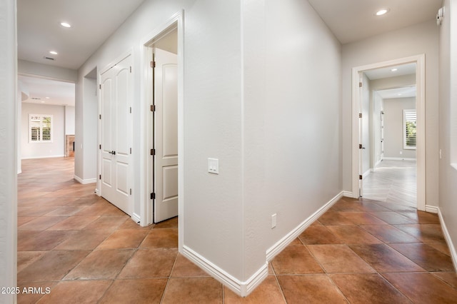 hall with recessed lighting and baseboards