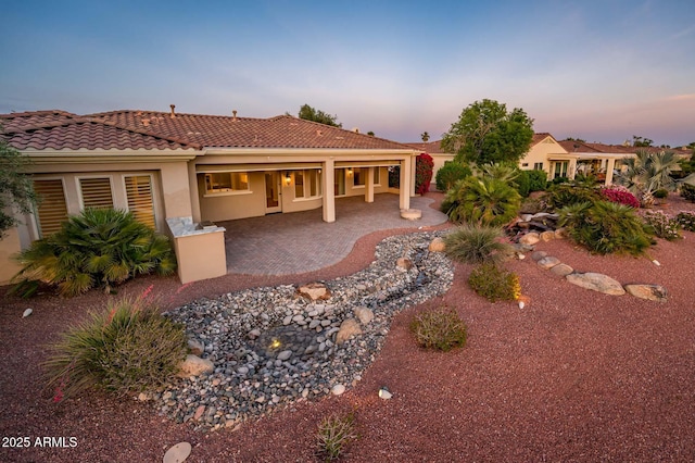 rear view of property featuring a tiled roof, a patio area, and stucco siding