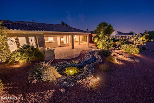 rear view of property featuring a patio area and a tile roof