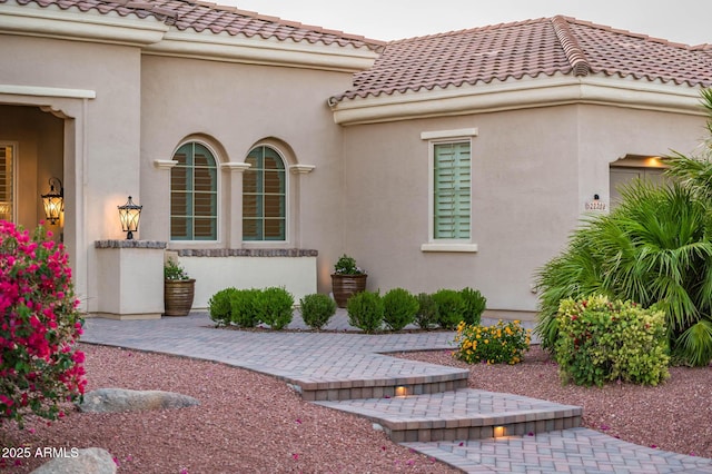 property entrance featuring a tile roof and stucco siding