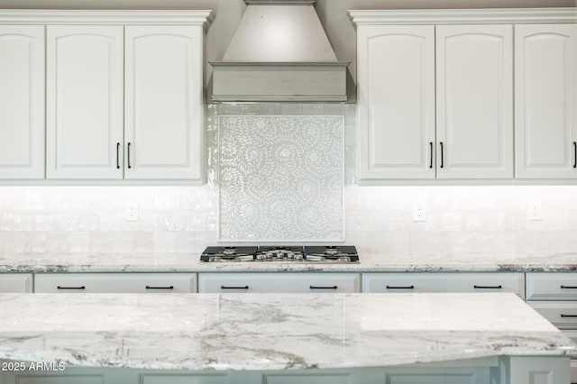 kitchen with white cabinets, stainless steel gas cooktop, custom exhaust hood, and backsplash