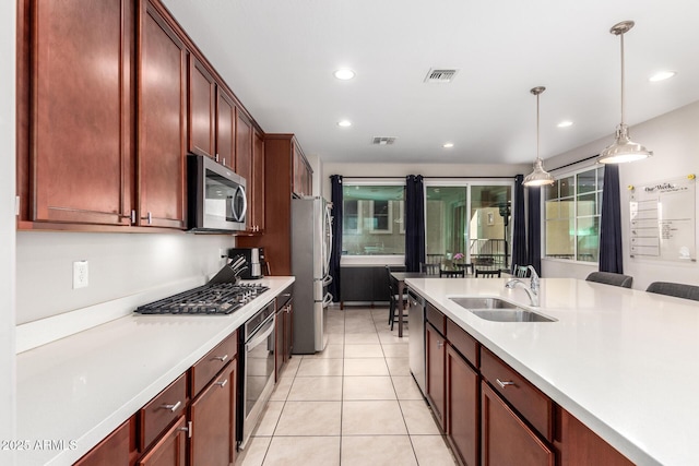 kitchen with decorative light fixtures, light tile patterned floors, sink, and stainless steel appliances