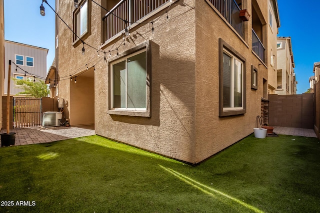 view of property exterior featuring a patio area, cooling unit, and a lawn