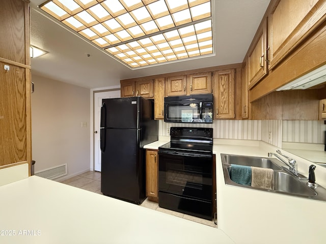 kitchen with sink, light tile patterned floors, and black appliances